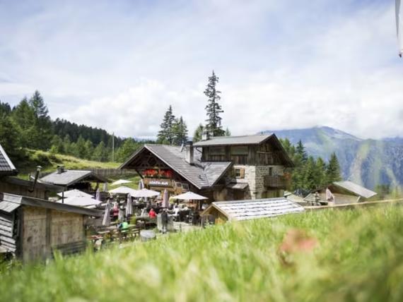 Hotel Adria in the mountains with outdoor seating and guests on a sunny day