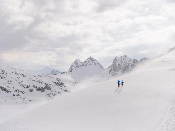 Zwei Personen wandern im Schnee mit Bergen im Hintergrund Hotel Aurora