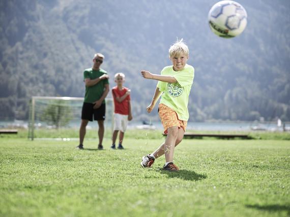 Kind spielt Fußball auf der Wiese im Familienresort Buchau