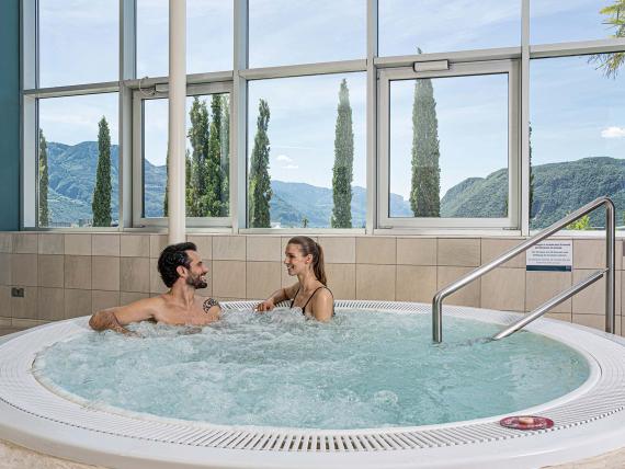 Coppia rilassata in vasca idromassaggio con vista montagna da 7th Heaven Beauty & Wellness