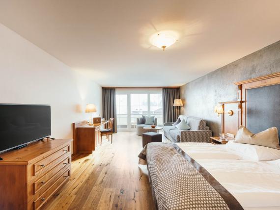 Helles Gästezimmer im Premium Activehotel Bergkönig mit Bett, TV und Sitzbereich