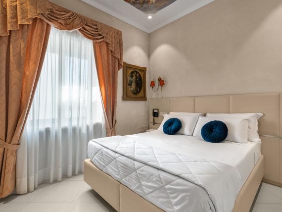 Camera da letto dell'Hotel Regina Caserta con letto matrimoniale e tende eleganti