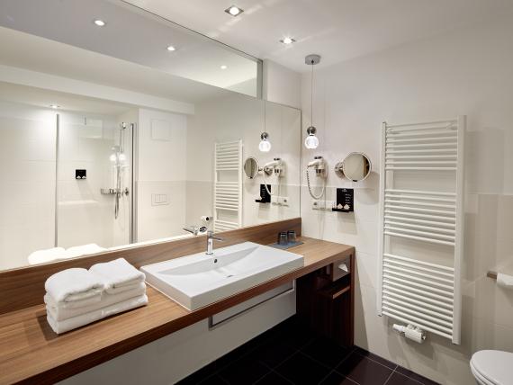 Modernes Badezimmer im Naturhotel Die Waldruhe mit Holzarbeitsplatte und großen Spiegeln