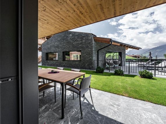 Hochfeldhof Terrasse mit Gartentisch, Stühlen und Blick auf Garten und Bergen