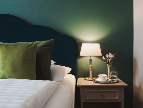 Cozy Hotel Adria room with green headboard and bedside lamp