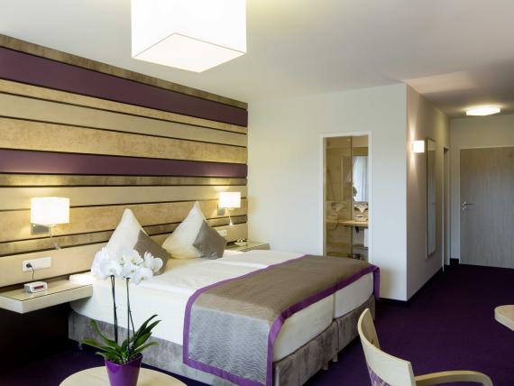 Modernes Hotelzimmer im Pfalzblick Wald Spa Resort mit Doppelbett und lila Akzenten