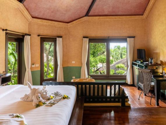 Interior of The Mangosteen Ayurveda & Wellness Resort room with bed and sofa