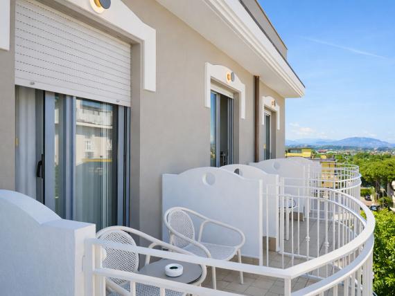 Balcone con sedie e tavolo al Regal Hotel Rimini con vista sul verde e le montagne