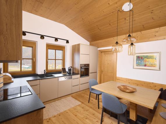 Moderne Küche mit Holzakzenten im Hochfeldhof mit Esstisch und zwei Stühlen