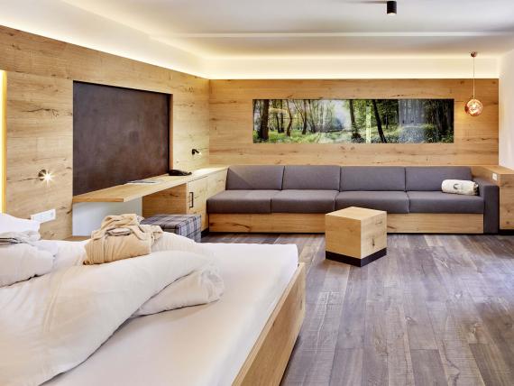 Gemütliches Zimmer im Naturhotel Die Waldruhe mit Holzelementen und großem Sofa.