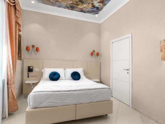Camera da letto dell'Hotel Regina Caserta con letto matrimoniale e soffitto decorato