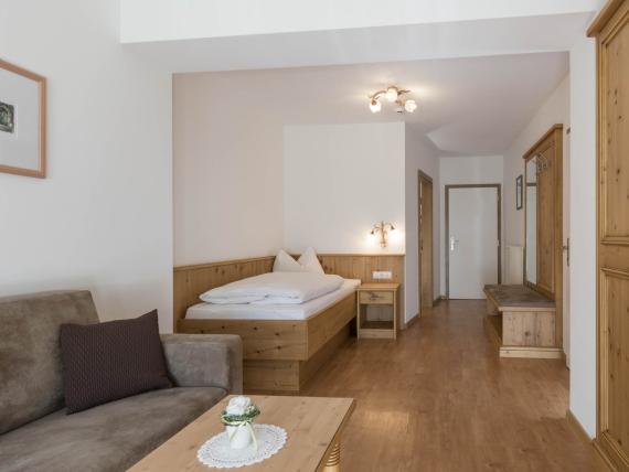Hotel Waldsee Zimmer mit Holzmöbeln, Bett und Sofa