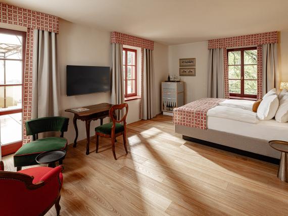 Helles Hotelzimmer mit Doppelbett und Sitzbereich im Castel Sallegg