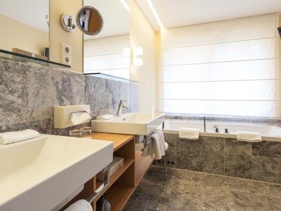 Modernes Badezimmer im Hotel Mignon Meran Park & Spa mit zwei Waschbecken und Badewanne