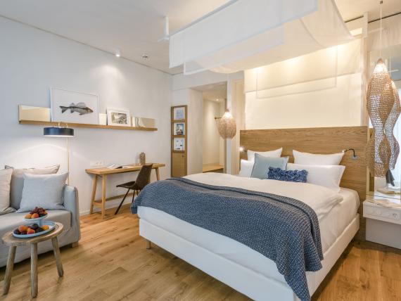 Modernes Schlafzimmer im Seezeitlodge Hotel & Spa mit Bett, Sofa und Schreibtisch