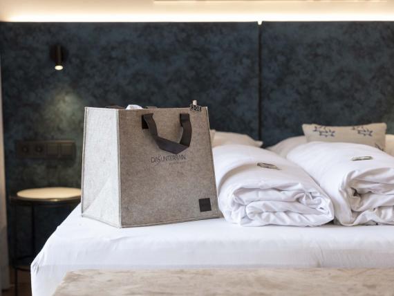 Letto matrimoniale con biancheria e borsa nell'Unterrain Lifestyle Hotel