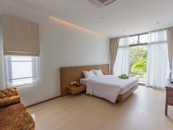 Bright bedroom with large window at The Mangosteen Ayurveda & Wellness Resort