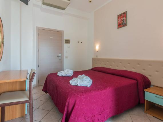 Camera con copriletto rosso e asciugamani piegati a forma di fiori