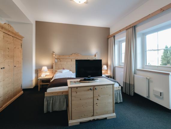 Helles Schlafzimmer mit Doppelbett und TV bei DER GREIL