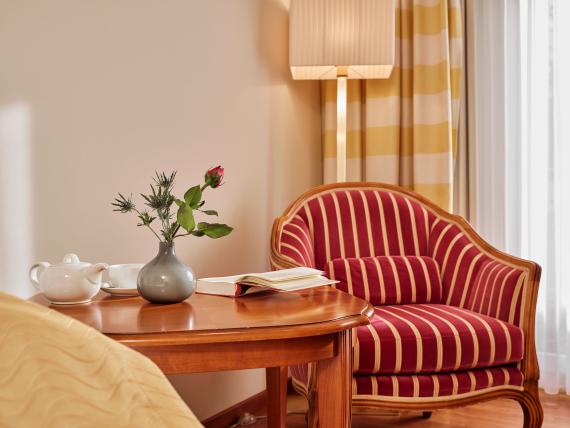 Gemütliche Sitzecke mit gestreiftem Sessel und Tisch im Hotel Reppert