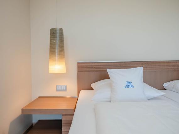 Gemütliches Hotelzimmer mit Bett und modernen Lampen im Parkhotel St. Leonhard Überlingen