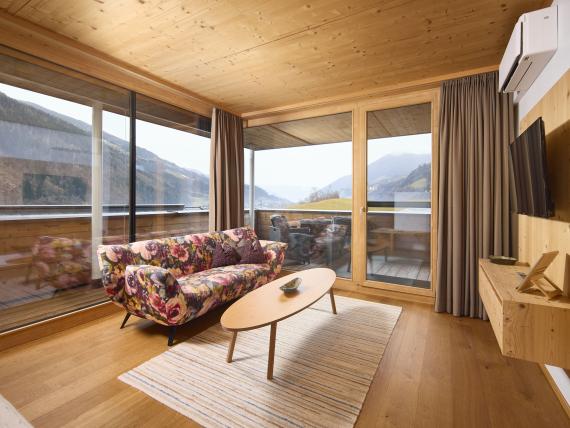 Gemütliches Wohnzimmer mit floralem Sofa und Blick auf Berge im Hochfeldhof