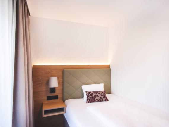 Der Dolomitenhof ***S modernes Einzelzimmer mit Bett und Nachttisch
