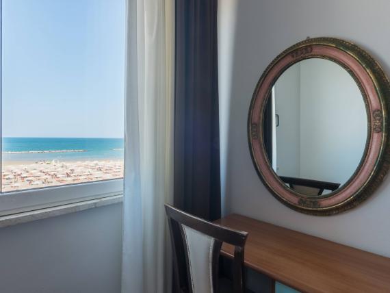 Stanza con fiori, specchio e vista mare dalla finestra