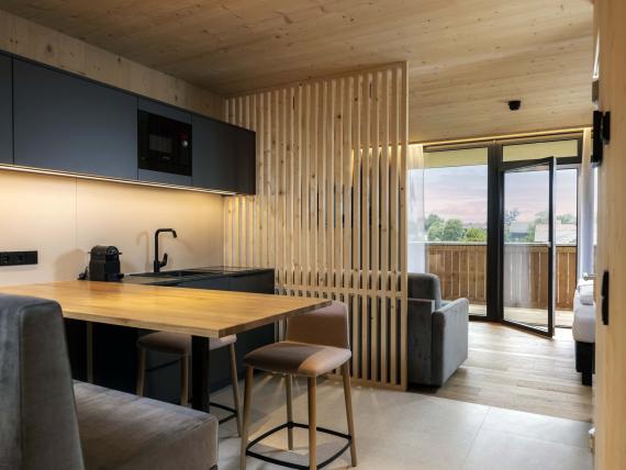 Der Dolomitenhof ***S moderne Küche und Essbereich mit Holzdetails und Balkon
