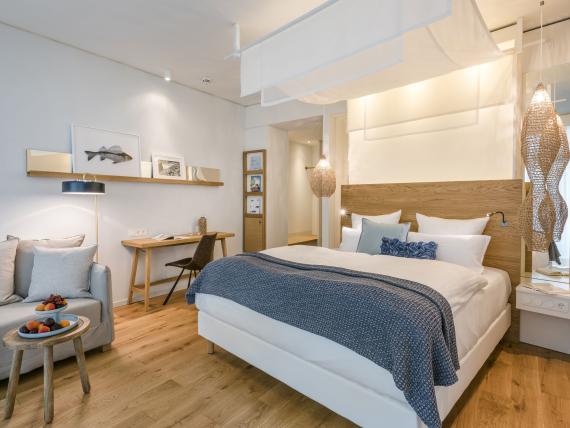 Modernes Hotelzimmer mit Bett und Sitzbereich im Seezeitlodge Hotel & Spa