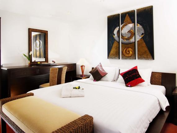 Cozy room with white bed and decorative pillows at The Mangosteen Ayurveda & Wellness Resort