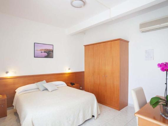 Camera d'albergo Hotel Viola Gaeta con letto matrimoniale, mobili in legno e orchidea