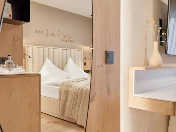 Helles Zimmer mit Doppelbett, Holzmöbeln und TV im Forster’s Naturresort