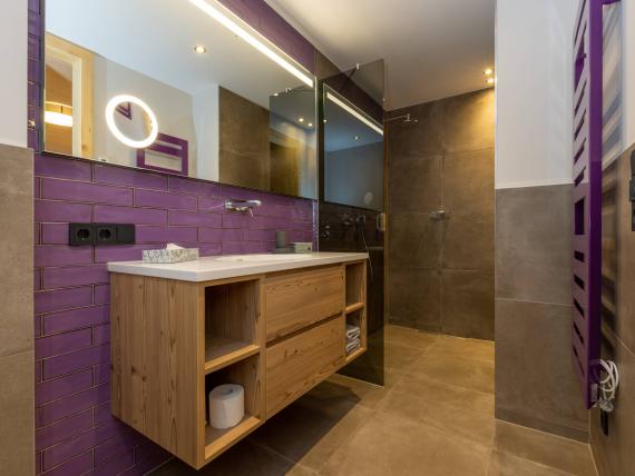 Moderne Badezimmer mit Holzmöbel und lila Fliesen im Hochfeldhof
