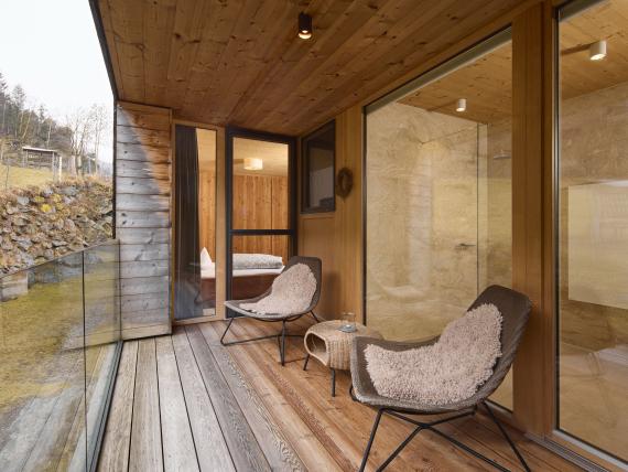Überdachter Balkon mit Stühlen und Blick auf Hochfeldhof und Landschaft