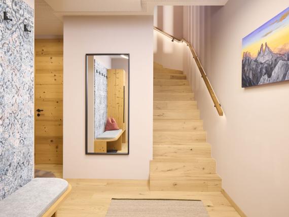 Heller Eingangsbereich mit Holztreppe und Sitzbank im Hochfeldhof