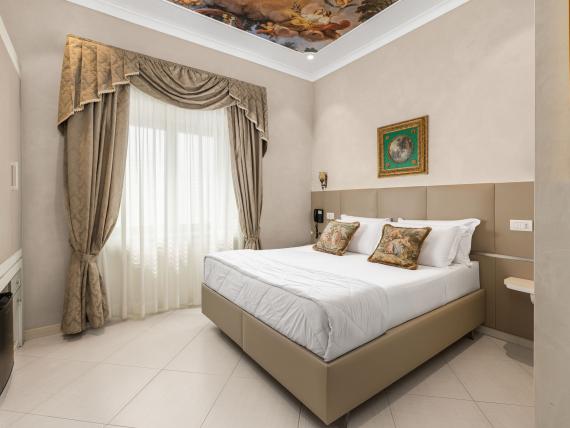Camera elegante all'Hotel Regina Caserta con soffitto decorato e tende