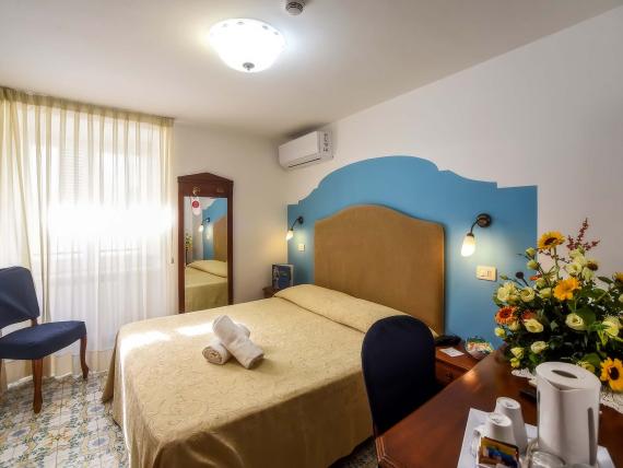 Camera dell'Hotel Amalfi con letto matrimoniale, sfondo blu e fiori