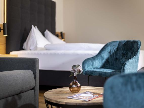 Gemütliches Hotelzimmer im Hotel Moarhof mit Blume auf Holztisch und blauen Sesseln