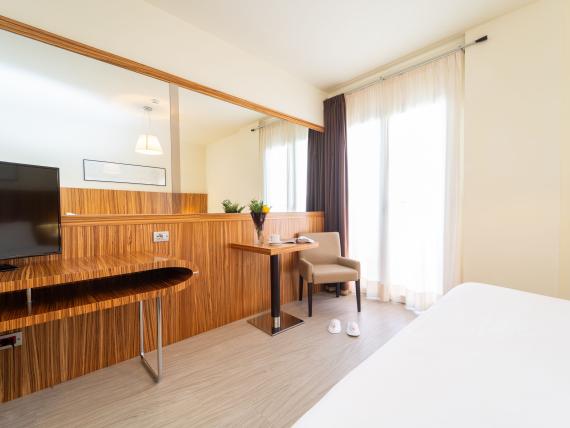 Camera d'hotel moderna con scrivania e TV al Bibione Palace Hotel