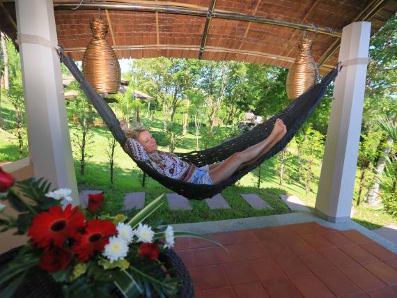Woman relaxing in a hammock at The Mangosteen Ayurveda & Wellness Resort patio