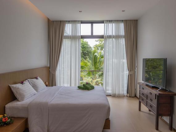 Modern bedroom with large window at The Mangosteen Ayurveda & Wellness Resort
