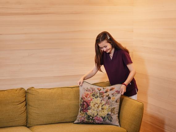 Hotel Aurora Mitarbeiterin richtet Sofakissen mit Blumenmuster her
