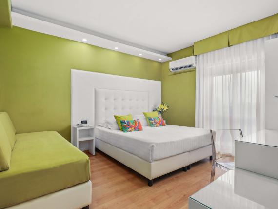 Camera accogliente al Reggia Suite Spa Hotel con divano verde e letto bianco