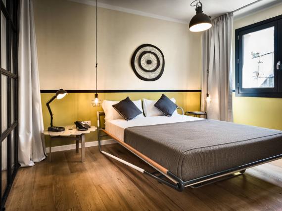 Camera da letto del Teku Boutique Hotel con letto matrimoniale, comodini e decorazione circolare a parete