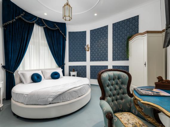 Camera elegante con letto rotondo e tende blu all'Hotel Regina Caserta
