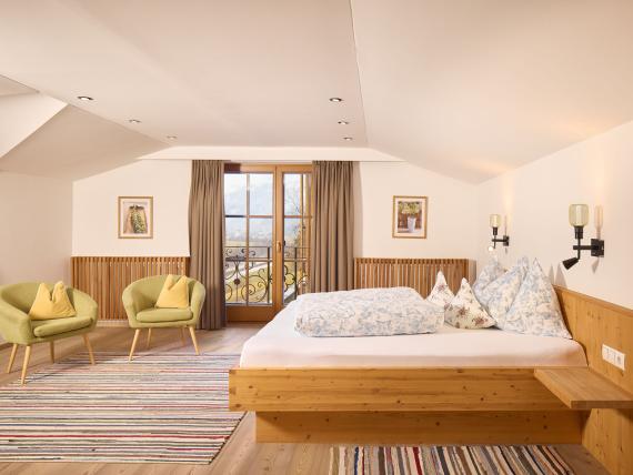 Helles Schlafzimmer mit Holzbetten und grünen Sesseln im Hochfeldhof