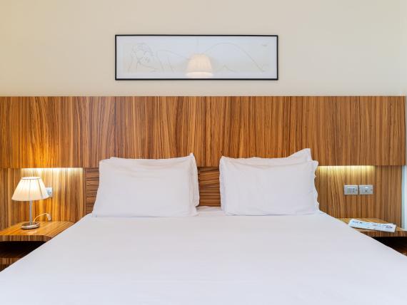 Letto matrimoniale con testiera in legno e lampade al Bibione Palace Hotel