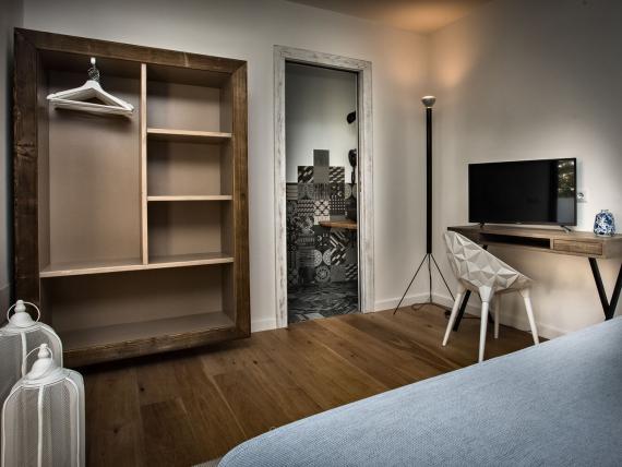 Camera del Teku Boutique Hotel con armadio aperto, TV, scrivania e porta del bagno