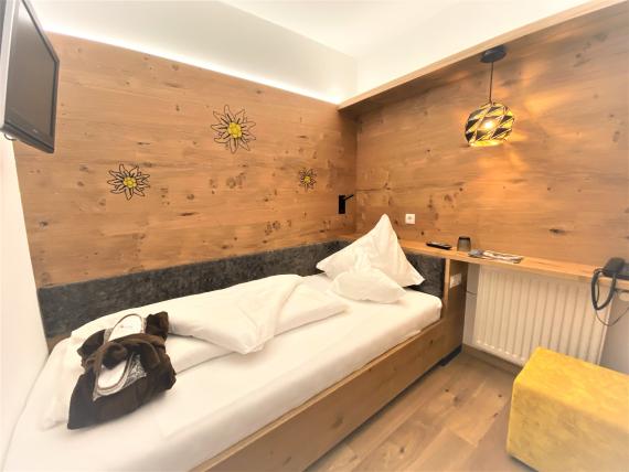 Einzelzimmer im Naturhotel Die Waldruhe mit Holzwand und Sonnenblumendekor